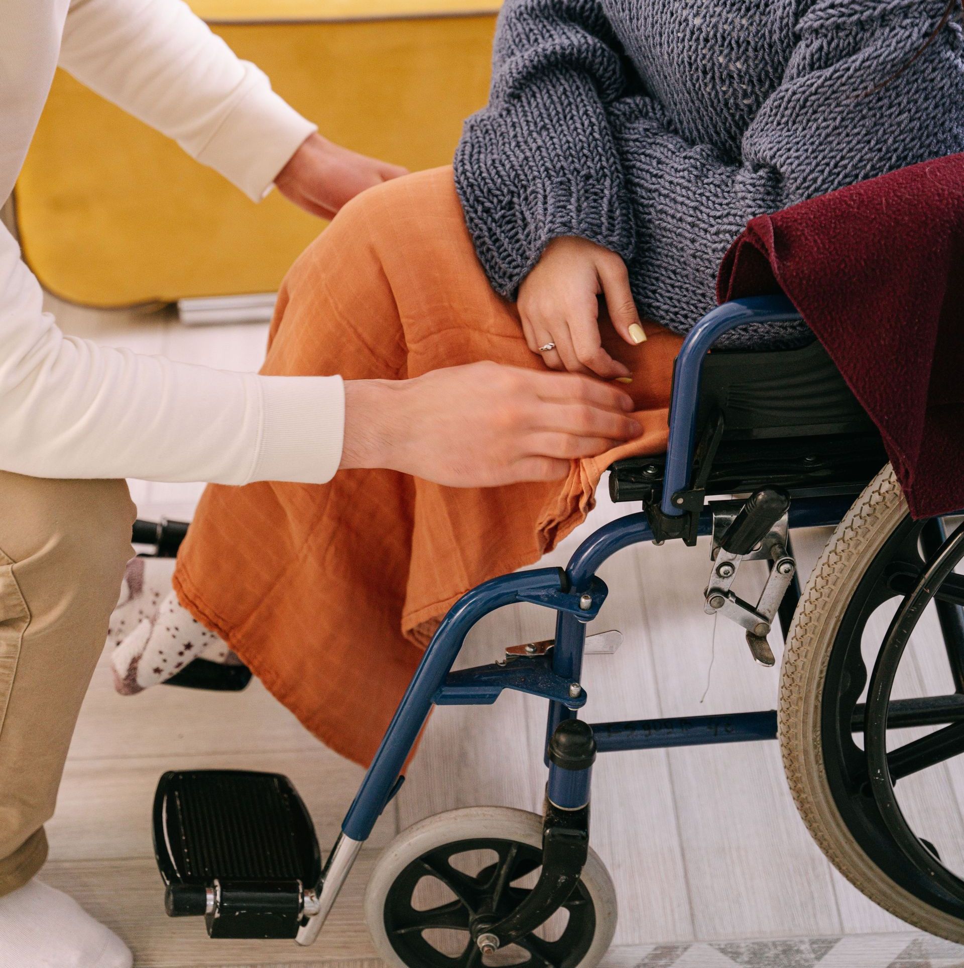 A supportive man assisting a woman in a wheelchair indoors, reflecting care and companionship.